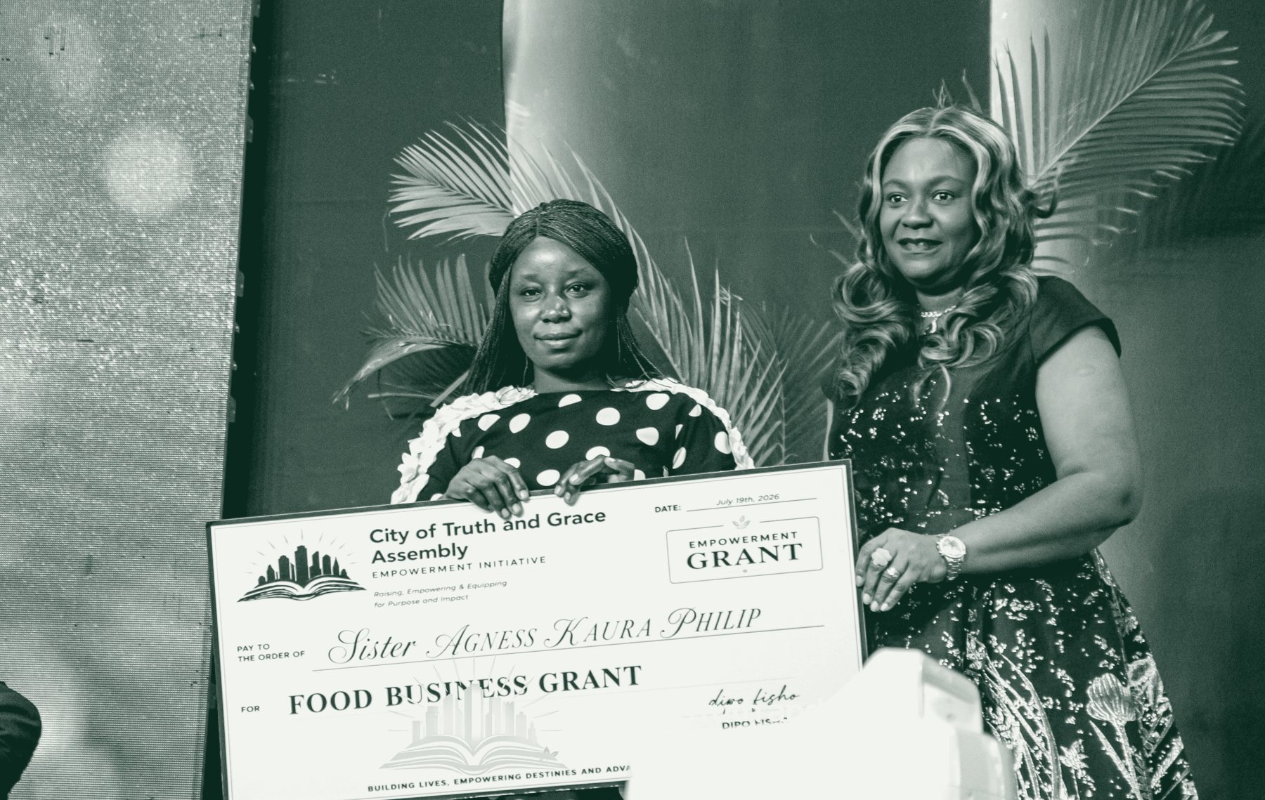 A grant recipient holds her food business grant cheque at a Fisho Initiative empowerment ceremony.